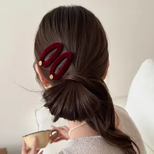 Nahaufnahme der dunkelroten Samt-Haarspange im dunklen Haar, eleganter Retro-Akzent.