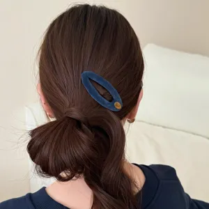 Detailaufnahme einer blauen Samt-Haarspange im braunen Haar mit feiner goldener Metallplakette.