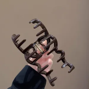 Nahaufnahme der dunkelbraunen Haarklammer mit einzigartigem Wellendesign und starker Metallfeder.