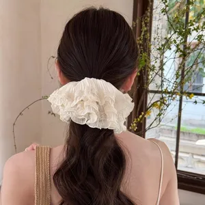 Detailed shot of a French vintage white ruffled lace hair scrunchie worn on a low ponytail.