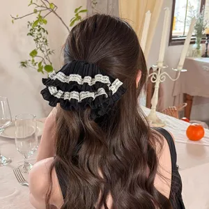 French lace hair scrunchie detail view displaying elegant black ruffled design worn on hair.