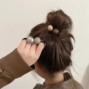 Close-up detail view of minimalist retro ball hair ties, elegant hair accessories for buns.