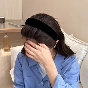 Detail shot of a black velvet headband worn by a model in a cozy indoor setting, soft lighting.