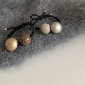 Minimalist retro glossy ball hair tie detail shot, perfect for elegant low ponytails and buns.