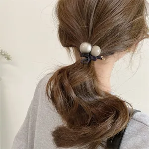 Close-up detail of the minimalist retro double ball hair tie, showing ponytail styling.