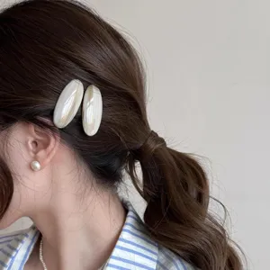 Close-up of elegant oval acetate hair clip worn on side, showing smooth marble texture.