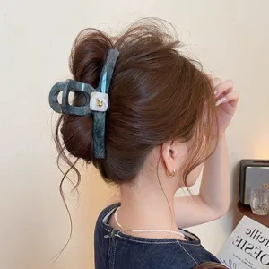 Detail shot of large marble hair claw clip featuring chic gold puppy accent for thick hair.
