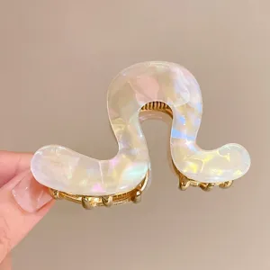 Close-up van parelmoer acetaat haarklem met gouden metalen tanden voor stijlvolle kapsels.