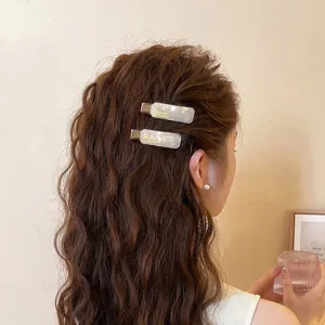 Detailansicht der modischen Acetat-Haarspange im welligen Haar, elegante Seitenhaarspange.