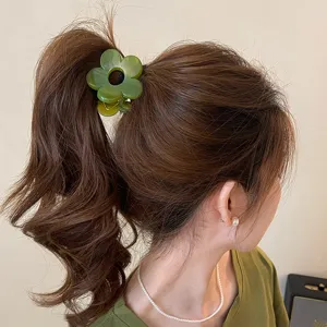 Vista dettagliata dell'elegante molletta per capelli a fiore verde, ideale per code di cavallo.