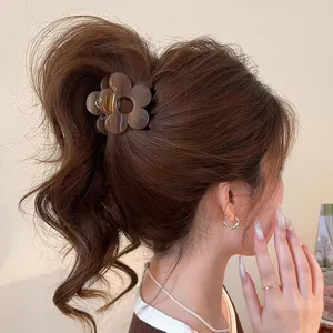 Vista dettagliata molletta per capelli a fiore marrone su coda alta, accessorio elegante.