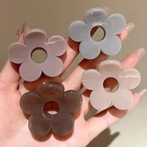 Primo piano di quattro eleganti mollette per capelli a fiore in colori pastello.