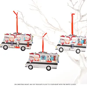 Vue détaillée d'ornements de bus de Noël en bois suspendus sur des branches blanches.