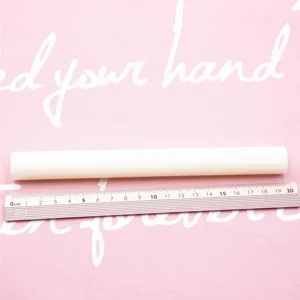White polymer clay rolling pin detail view displaying length with ruler on pink mat.