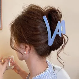 Gros plan sur une élégante pince à cheveux géométrique pailletée bleue sur un chignon.
