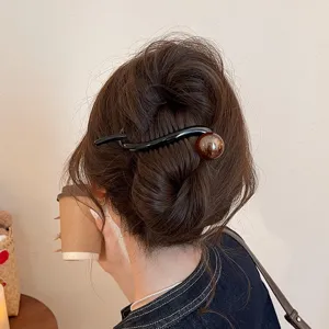 Detailed lifestyle shot showcasing a black wave hair clip with brown bead worn on a bun.