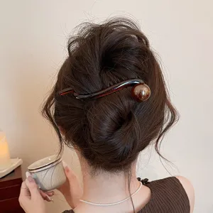 Detailed view of elegant brown hair stick twist clip for stylish summer buns and daily hairstyles.