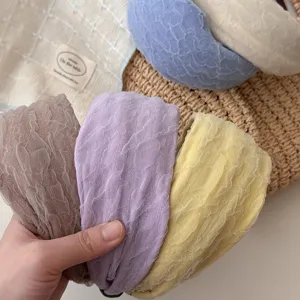 Dettaglio di cerchietti larghi in chiffon pastello, tessuto stropicciato morbido.