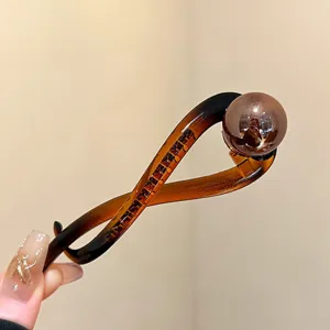 Close-up detail of the elegant brown resin twist hair claw clip with a large round pearl.