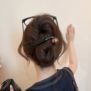 Close-up detail of a stylish black wavy hair stick with a brown bead for elegant chic updos.