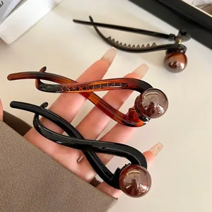 Detailed view of elegant pearl twist hair claw clip in amber and black for styling updo hairstyles.
