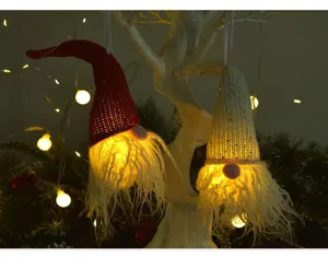 Gros plan de décorations suspendues de gnomes lumineux pour sapin de Noël avec LED et bonnets.