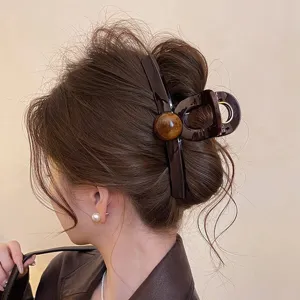 Gedetailleerd opname van de bruine haarspeld met ronde kralendecoratie, elegante haarklem voor dames.