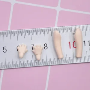 Miniature doll hands and arms detail view showing scale and size on ruler background.