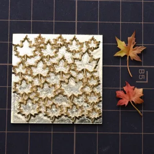 Detailed brass mold plate with intricate maple leaf patterns for miniature clay crafts.