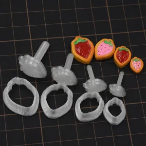 Closeup view of 3D printed strawberry cookie cutter molds and cute clay charms in detail.
