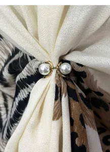 Close-up detail of stylish leopard print scarf with elegant double pearl buckle accessory.