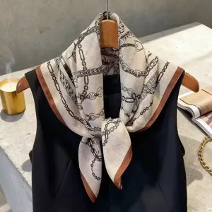 Detail view of a chic square scarf featuring chain and horse motifs with a brown border.
