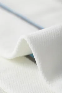 Close-up view of premium white compression fabric showing fine texture and elastic knit design.