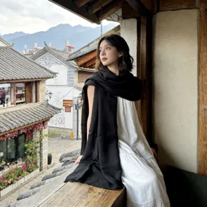 Detailed view of a lightweight oversized solid black scarf shawl worn by an Asian model outdoors.