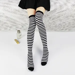 Close-up detail view of black and white striped over-the-knee socks worn in a daily scene.