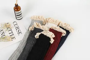 Detailed view of women's over-the-knee socks featuring delicate lace ruffles and knit pattern.