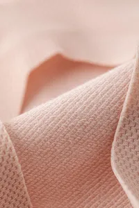 Close-up view of soft pink breathable stretch knit fabric texture, fine detail shot.