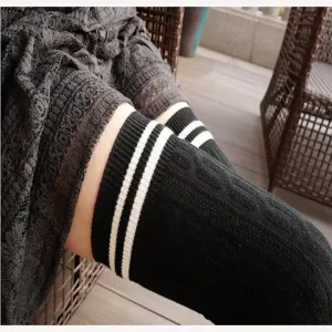 Close-up of black over-the-knee socks featuring white stripes and cable knit texture.