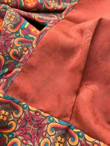 Primo piano della sciarpa in seta bisiemble con stampa cachemire e jacquard ruggine.