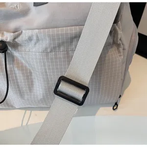Vue détaillée de la bandoulière réglable, de la boucle et du tissu à carreaux du sac de voyage.