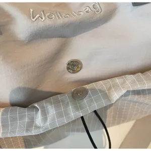 Détail en gros plan du sac de voyage sport montrant le bouton-pression et le logo brodé.