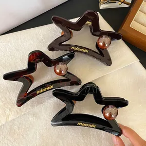 Primo piano dettaglio di grande molletta per capelli stella cava con perla, accessorio.