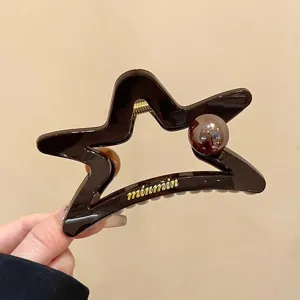 Primo piano dettagliato della molletta per capelli a stella marrone scuro, accessorio elegante.