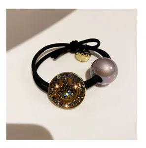 Rhinestone smiley face pendant close-up, iridescent pearl and black elastic hair tie detail view.