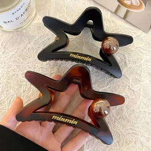 Primo piano dettaglio del grande mollettone per capelli a stella con eleganti perle.
