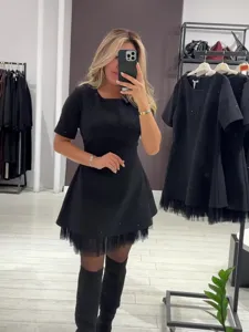 Detailaufnahme des schwarzen Kurzarm-Strasskleides mit Tüllsaum in der Boutique-Kulisse.