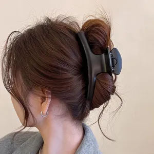 Matte schwarze geschwungene Haarklammer, große Haarklammer Detail für elegante Frisuren.