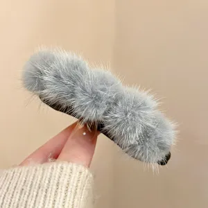 Detailed close-up of a soft grey plush hair claw clip with a fluffy furry texture.
