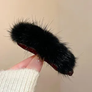 Close up of a winter black plush fur hair clip detail, showing soft fluffy texture and design.