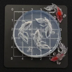 Close-up detail of miniature goldfish silicone mold for resin and clay crafts, clear grid.